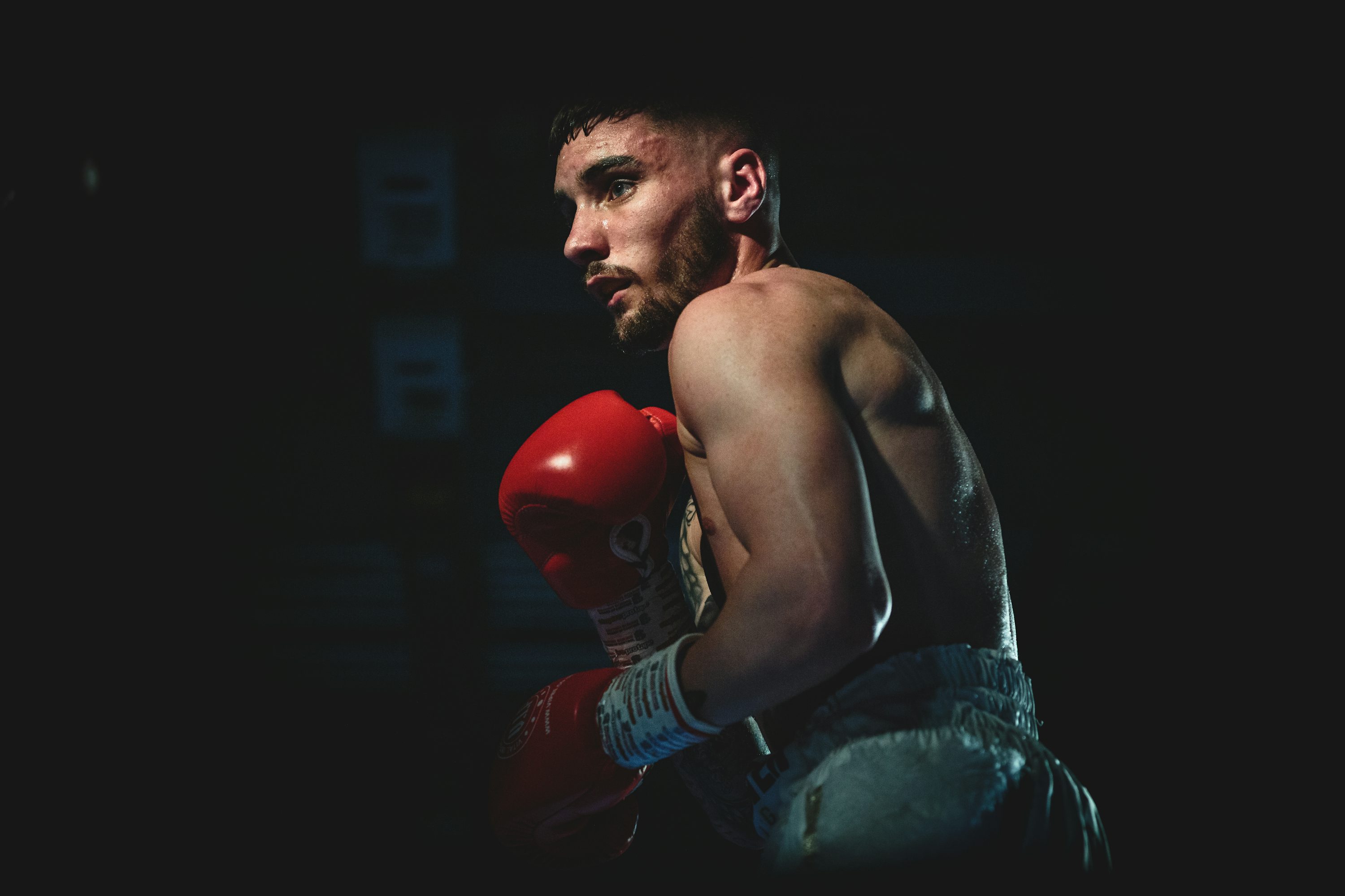 Atleta de boxe em posição de combate, demonstrando técnica e preparação física